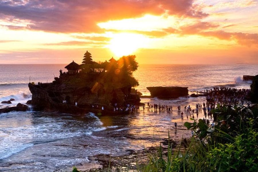Sunset view at Tanah Lot Temple Bali with waves crashing on the rock formation
